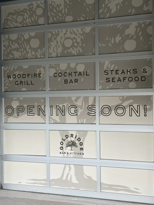Gold Ridge Bar & Kitchen storefront window reading Woodfire Grill, Cocktail Bar, Steaks & Seafood — Opening Soon